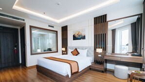 Een moderne hotelkamer met een groot bed, een kaptafel met spiegel en uitzicht op het groen.