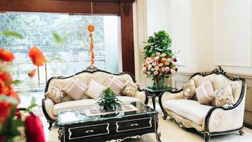 Una habitación con dos sofás decorados, una mesa de centro de cristal y un arreglo floral.