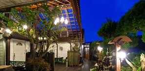 A wooden deck with a pergola, outdoor seating, and a small garden area with a lantern. - Taean White Sand Pension (Taean)