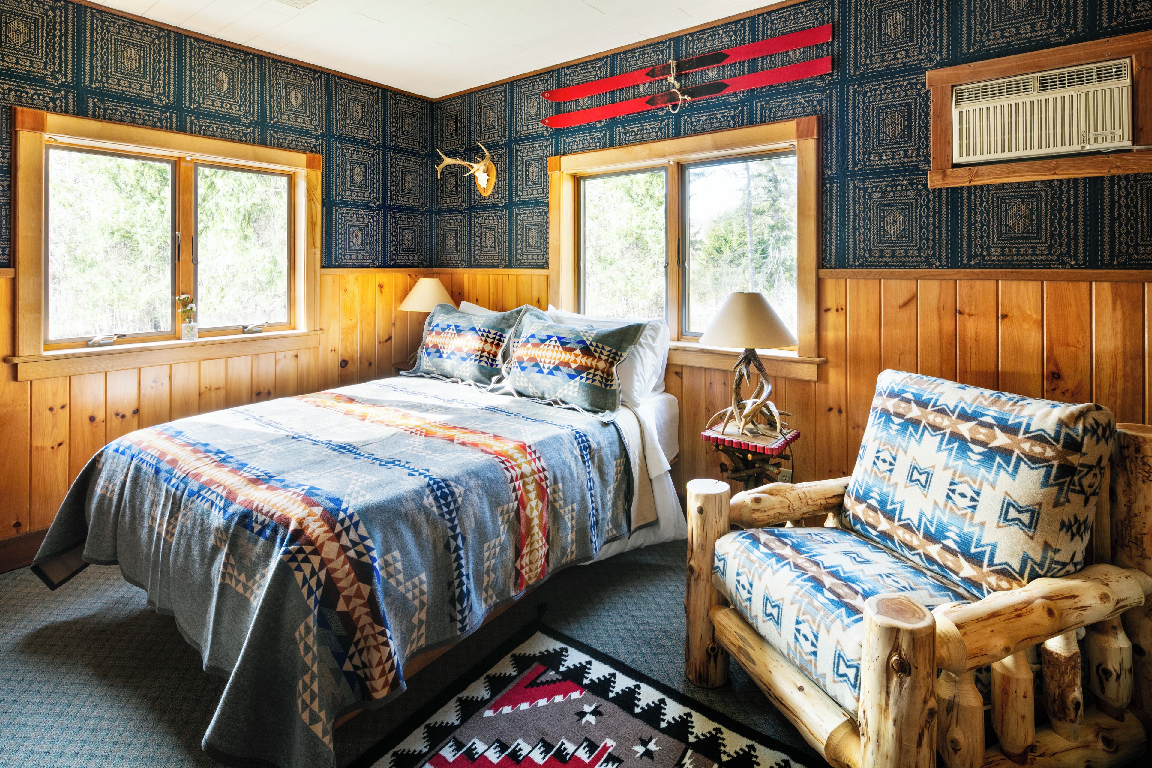 Una habitación acogedora con una cama, una silla de madera y una ventana con vistas a árboles.
