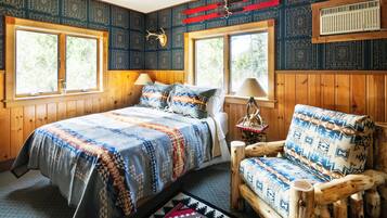 Una habitación acogedora con una cama, una silla de madera y una ventana con vistas a árboles.
