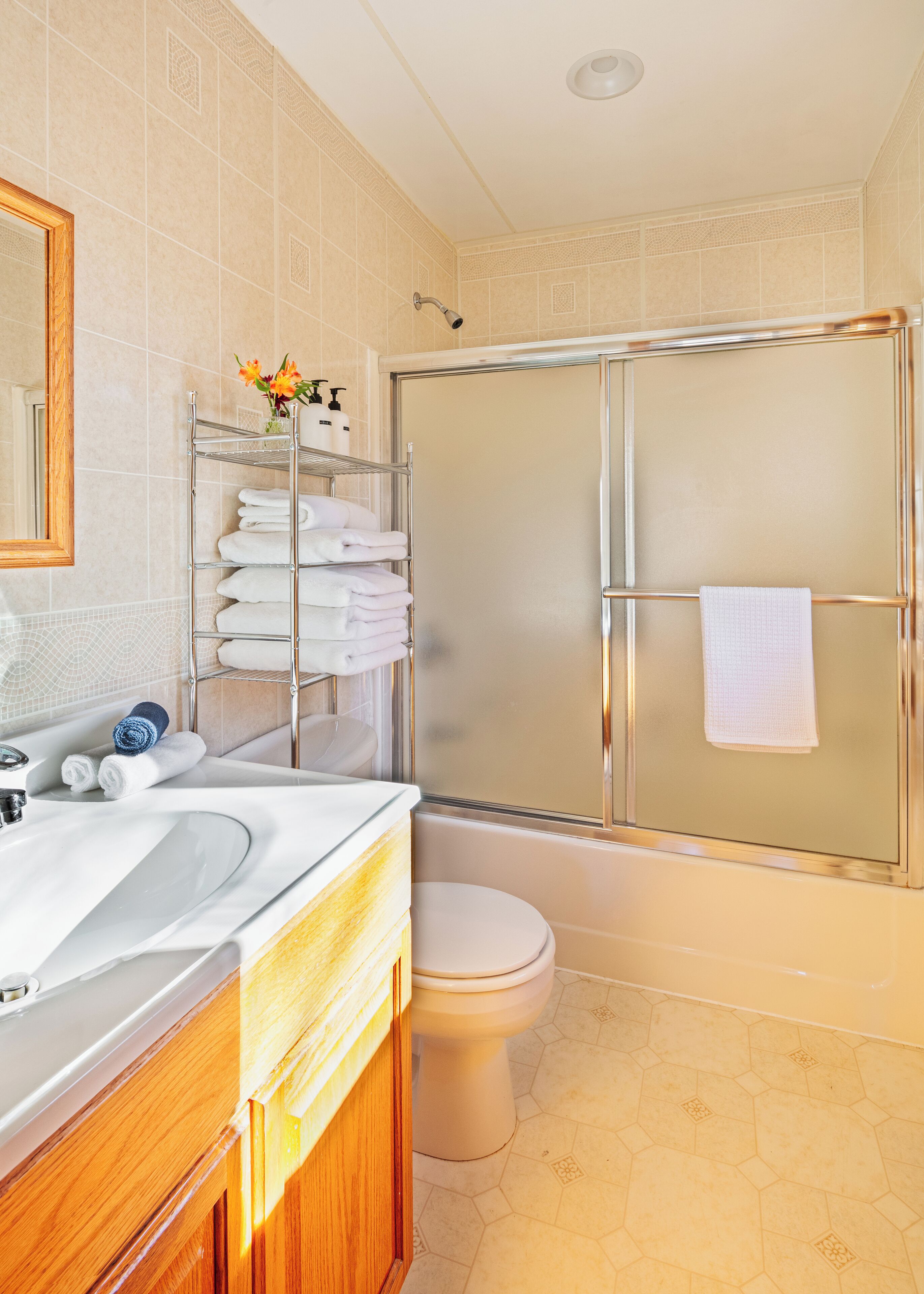 A modern bathroom with a glass shower enclosure, a white toilet, and a vanity with a mirror and towel rack.