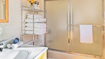 A modern bathroom with a glass shower enclosure, a white toilet, and a vanity with a mirror and towel rack.