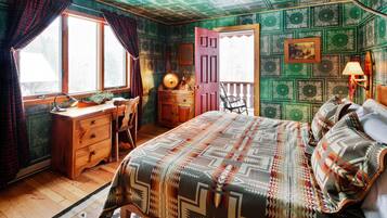 A cozy room with a bed, a desk, and a chair. There is a window with curtains, a lamp, and a door leading outside.