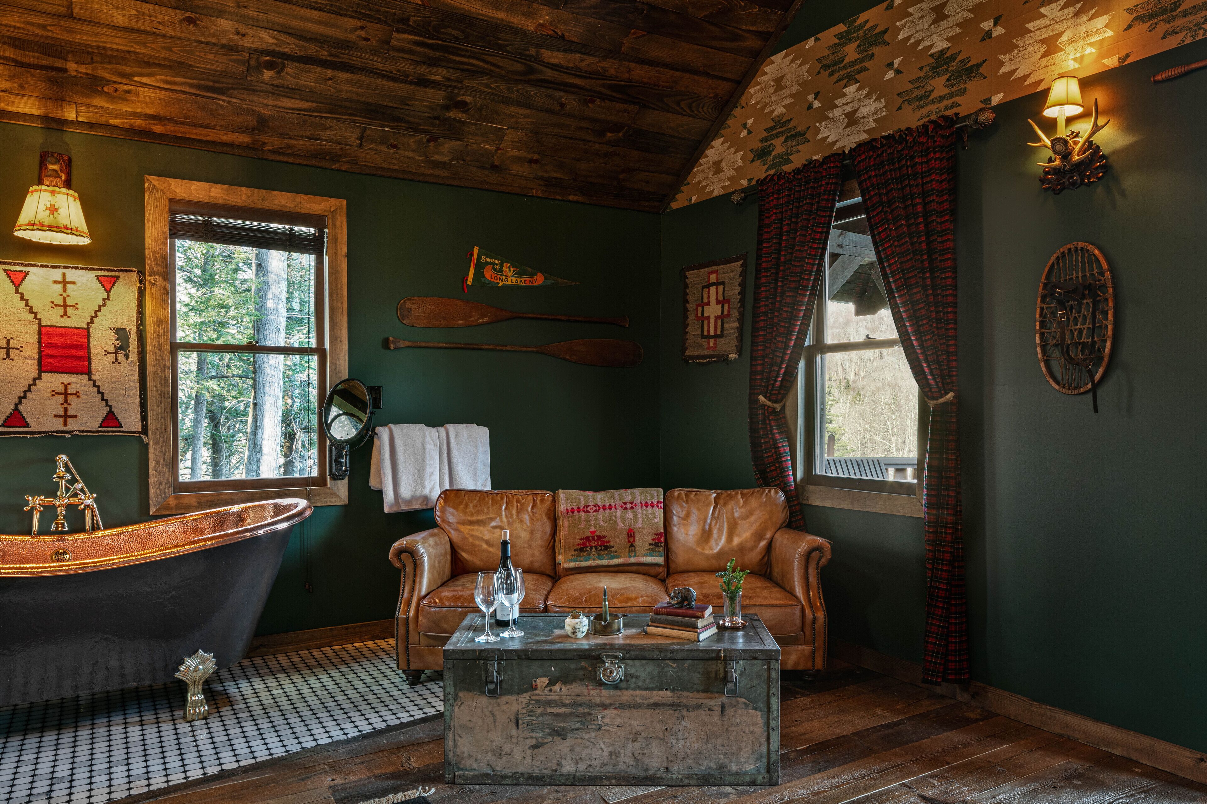 Une pièce au décor rustique, dotée d’une grande baignoire, d’un canapé en cuir et d’une table basse en bois.