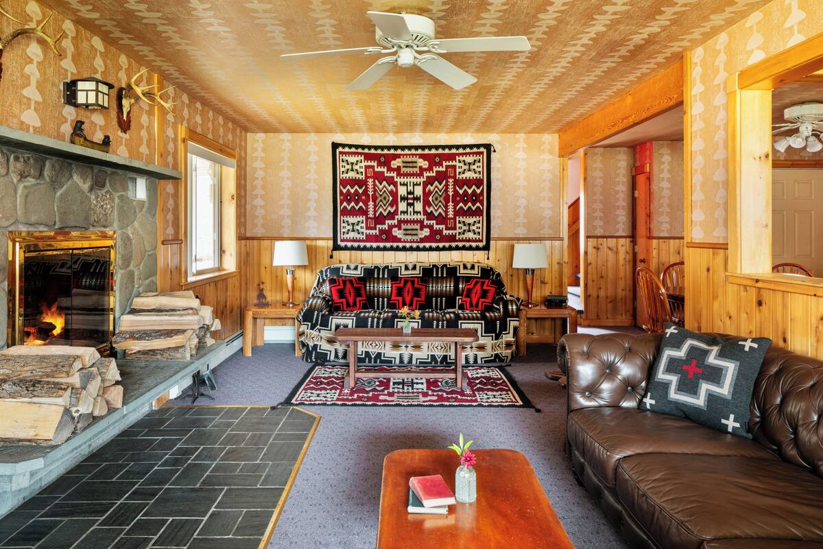 A cozy living room with a fireplace, leather sofa, and a patterned rug.