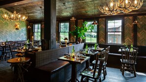 A rustic interior with wooden beams, a chandelier, and a seating area with tables and chairs.