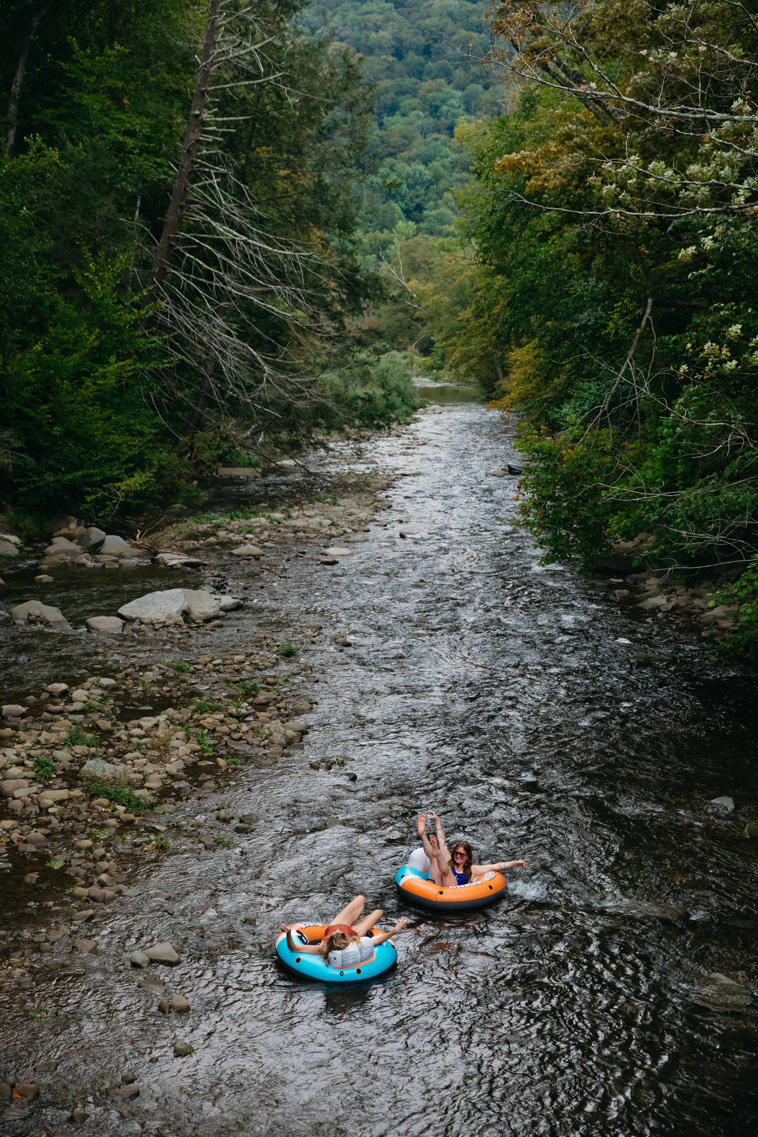 A river with two people on inflatable tubes.