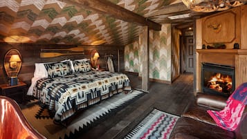 A cozy room with a bed, a fireplace, and a leather armchair.
