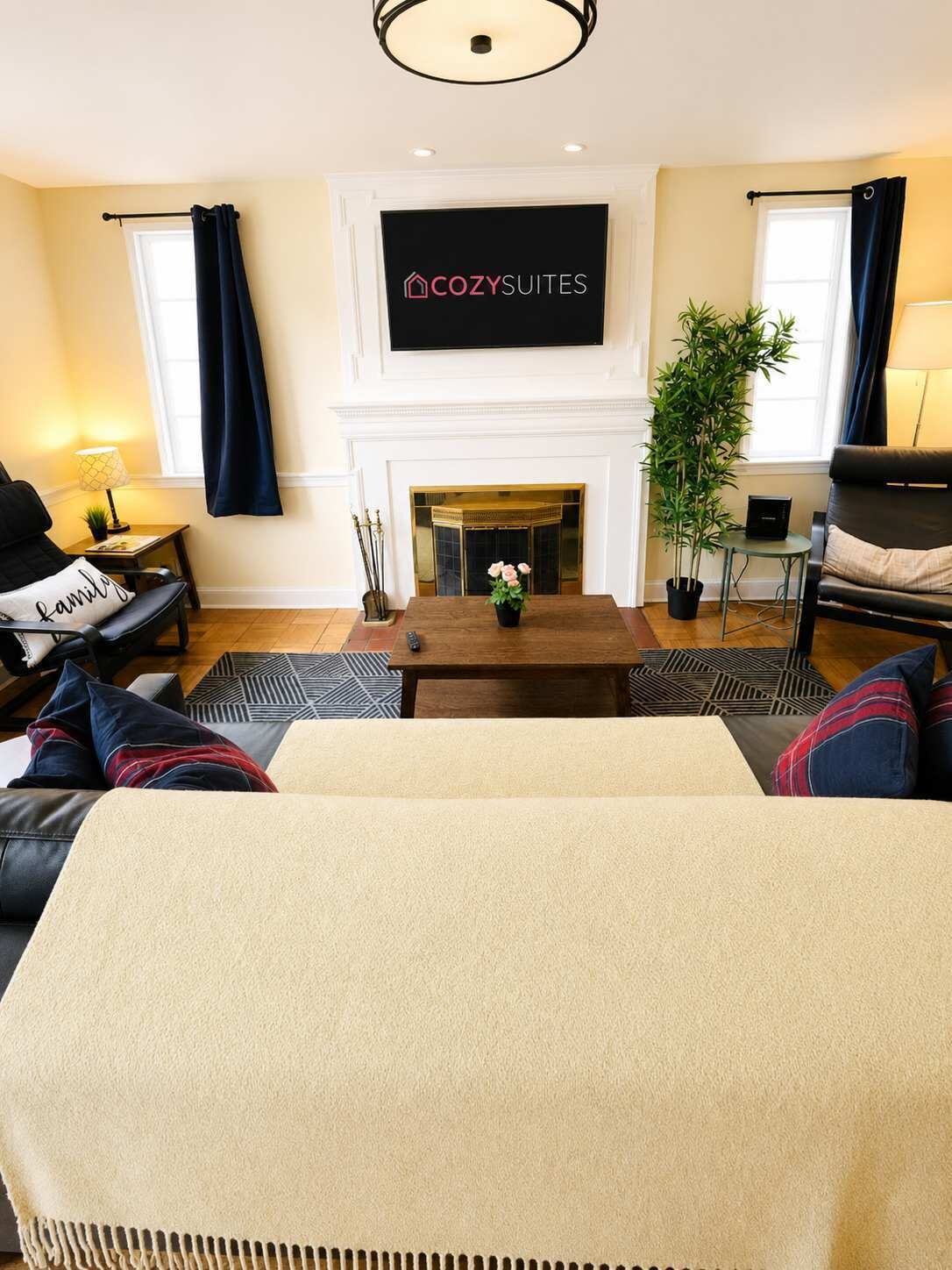 A living room with a fireplace, a sofa, a coffee table, and a TV mounted above the fireplace.