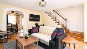 A living room with a sofa, coffee table, and a dining area with chairs and a table.