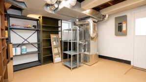 A room with a metal shelving unit, a large mirror, and ductwork on the ceiling. - Spacious 4BR CozySuites in Old Town Alexandria (Alexandria)