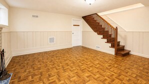 A room with a wooden herringbone floor, a wooden staircase, and a white door. - Spacious 4BR CozySuites in Old Town Alexandria (Alexandria)