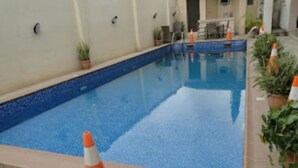 Une piscine dont le bord est revêtu de carreaux, avec quelques plantes en pot disposées autour.