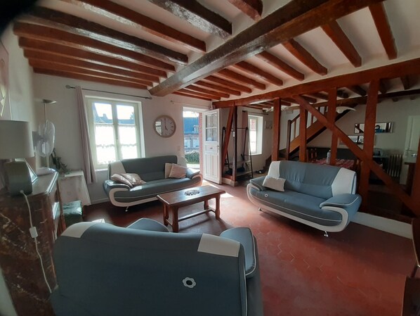 A spacious living room with two sofas, a coffee table, and a wooden ceiling with exposed beams.