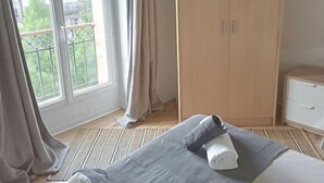 Une chambre d’hôtel avec un grand lit, une armoire, une table de chevet et une fenêtre avec des rideaux.