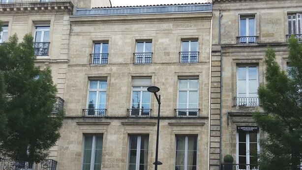 Un immeuble à plusieurs étages, de style architectural classique, doté de balcons et de grandes fenêtres.