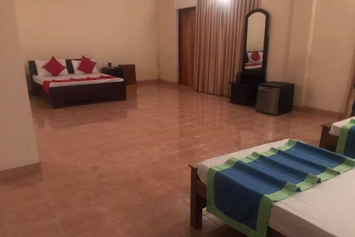 A hotel room with a bed, a bedside table, a mirror, and a curtain.