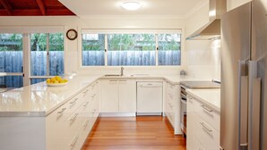 A modern kitchen with white cabinetry, a stainless steel refrigerator, and a wooden floor.