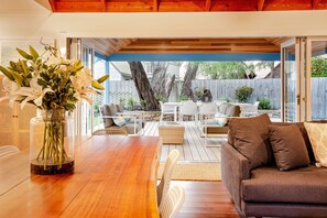 An outdoor patio area with a wooden table, white chairs, and a brown sofa. - Blue House: one street from the beach (Quindalup)