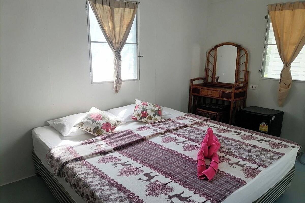 A bedroom with a bed, a wooden dresser, and a mirror.