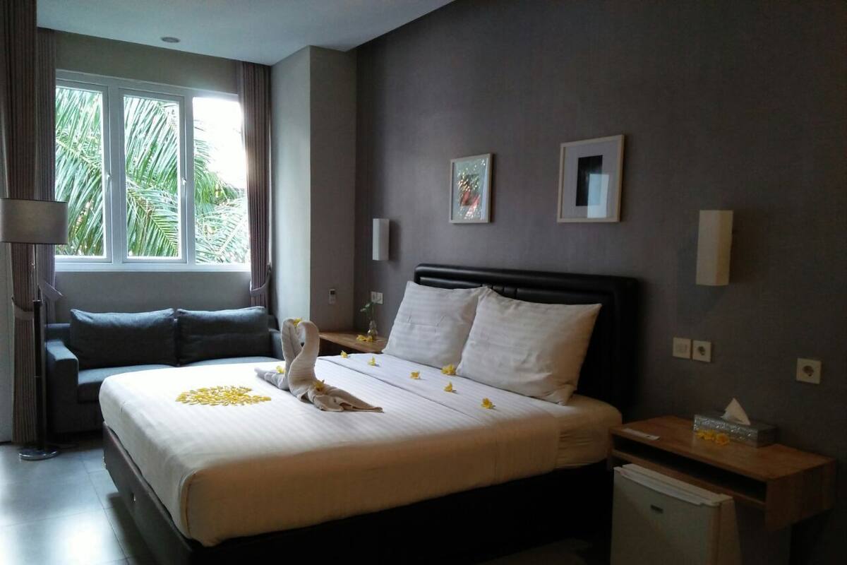 Una habitación de hotel con una cama, una mesita de noche, una lámpara y una pequeña mesa.