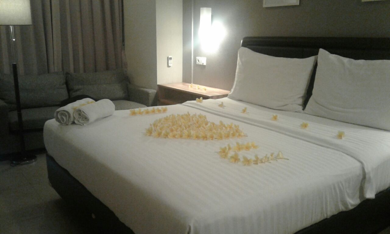 Una habitación de hotel con una cama bien hecha, un sofá y una mesita de noche.