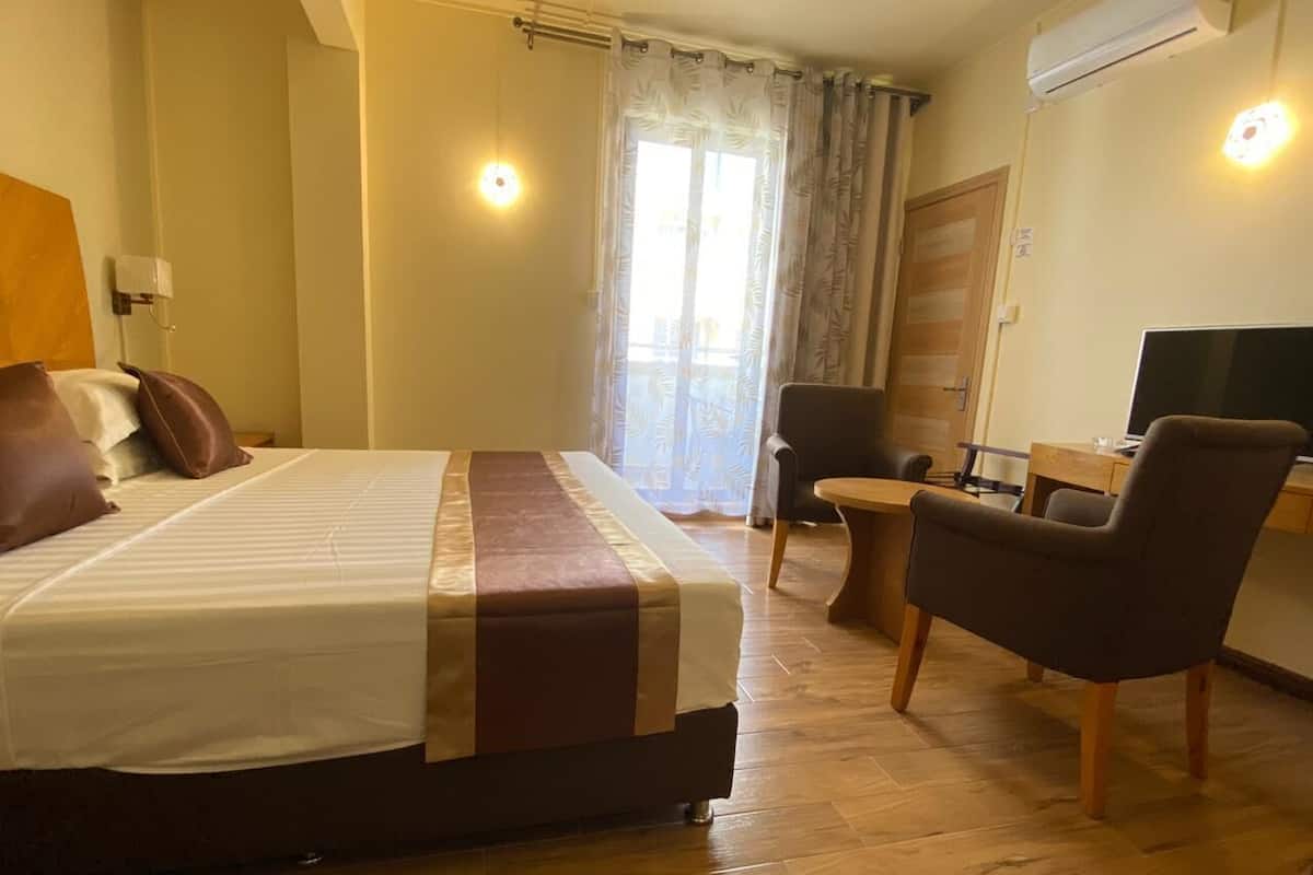 A hotel room with a bed, a desk, a chair, and a TV.
