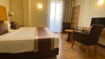Een hotelkamer met een bed, een bureau, een stoel en een televisie.