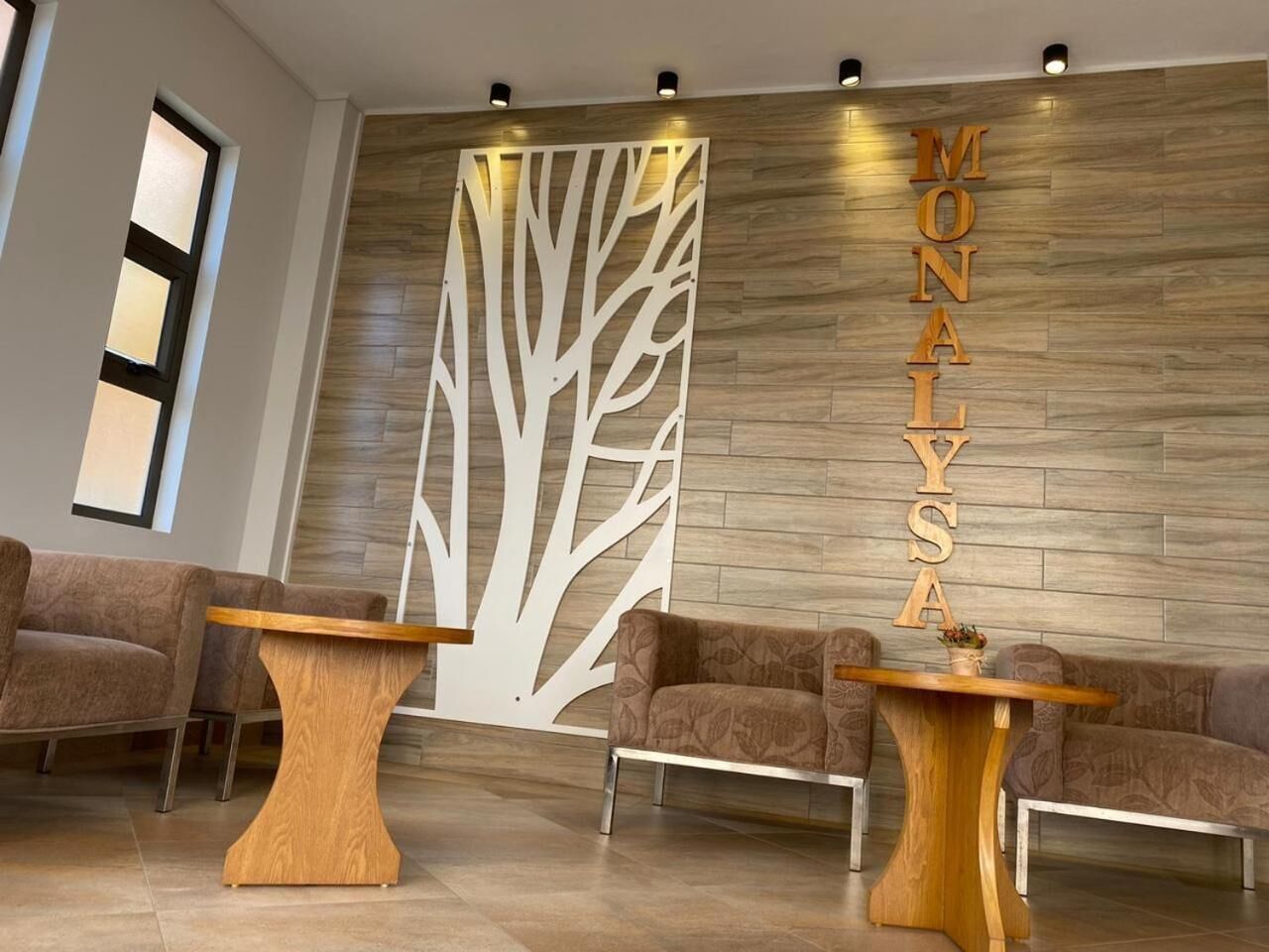 A reception area with a wooden wall, two sofas, and two wooden tables.