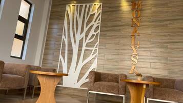 A reception area with a wooden wall, two sofas, and two wooden tables.