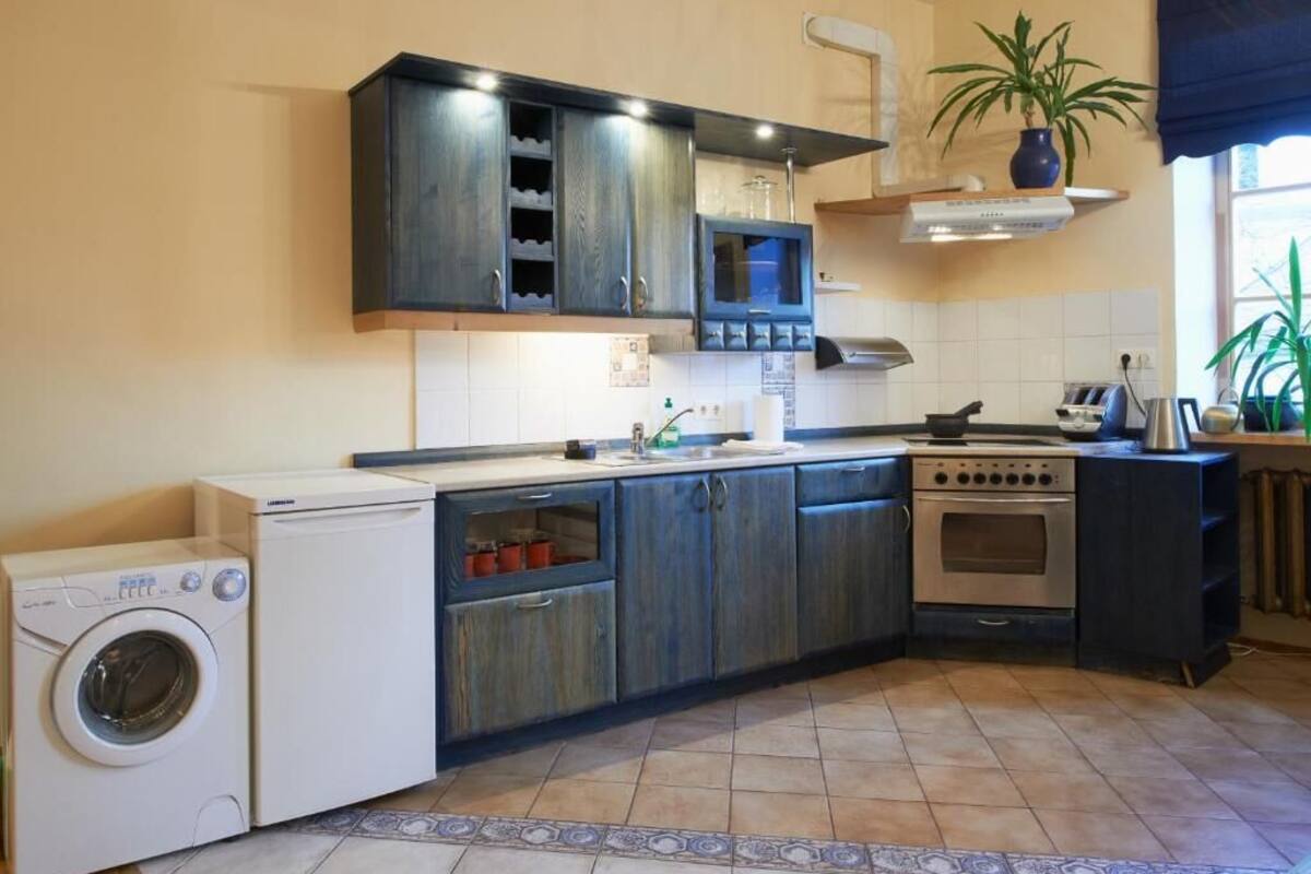 A compact kitchen with a washing machine, microwave, oven, and a small sink.