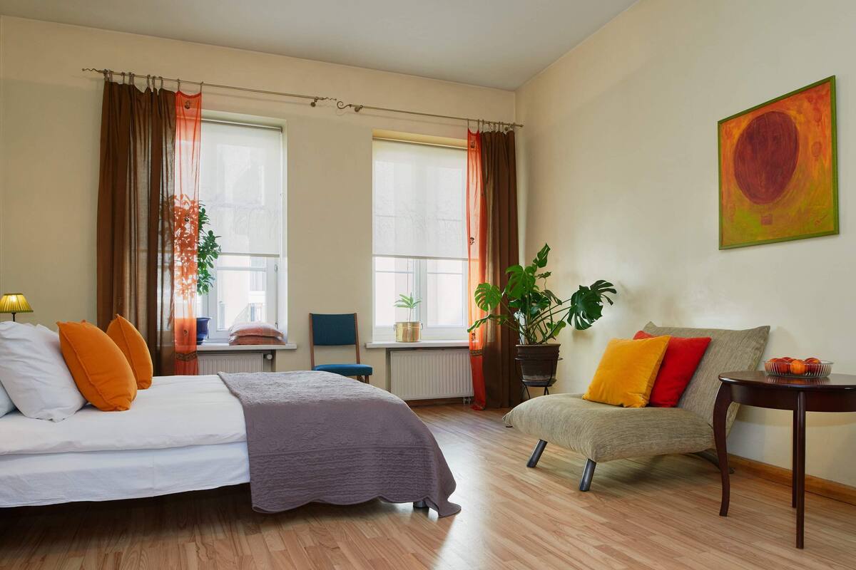 A hotel room with two beds, a sofa, a small table, and a potted plant.