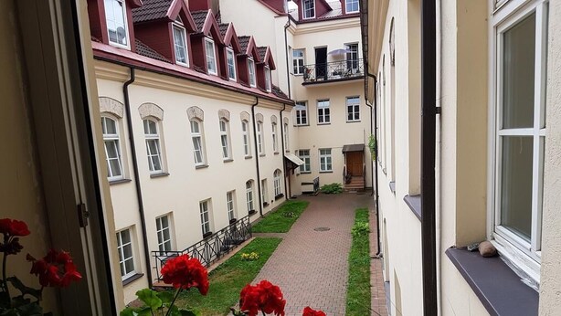 En smal innergård med en gångstig av tegelstenar, omgiven av höga byggnader med balkonger.