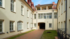 En innergård med en gångstig av tegelstenar som leder fram till en byggnadsingång.