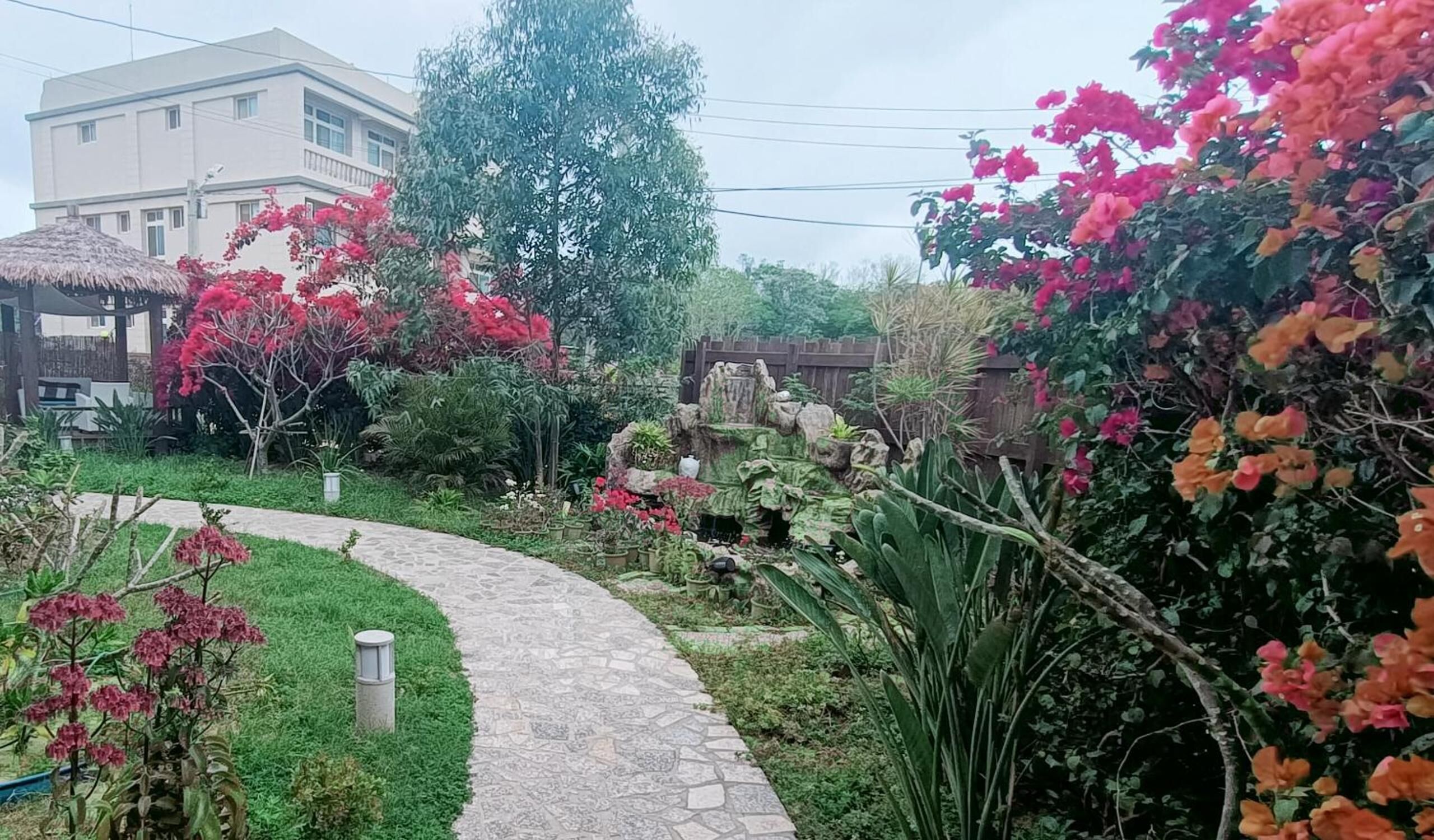 Un sendero en un jardín que lleva a un edificio con techo de paja.