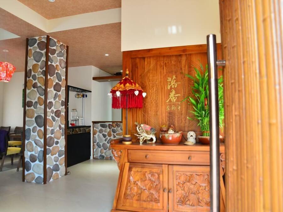 Un interior japonés tradicional con un mostrador de recepción de madera, un pilar de piedra y una lámpara colgante roja.