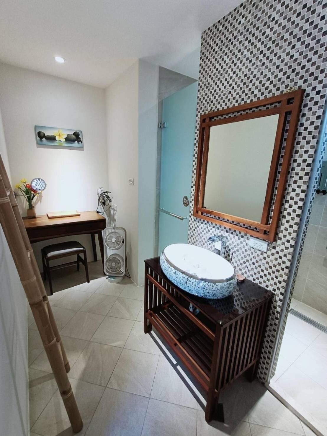 Une salle de bain avec un lavabo rond, un miroir et un mur recouvert de carreaux.