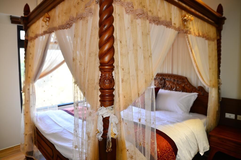 Een hemelbed met houten frame en decoratieve hemel.