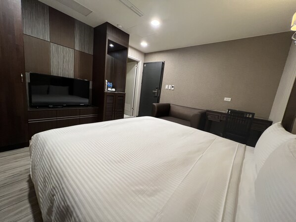 A hotel room with a large bed, a flat-screen TV, a wardrobe, and a desk with a chair. - Maple Hotel Second Branch (Tainan)