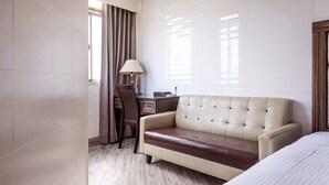 Ett hotellrum med en säng, en soffa, ett skrivbord och en stol.
