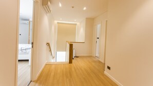 A hallway with wooden flooring, white walls, and a staircase leading to another room. - The Point Villa (Da Nang)