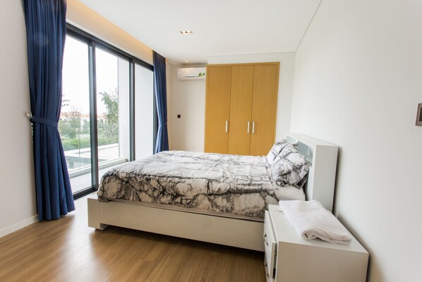 A bedroom with a bed, a wardrobe, and a window with curtains. - The Point Villa (Da Nang)