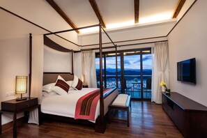 Ein Himmelbett mit Blick auf eine Stadtlandschaft durch große Fenster.