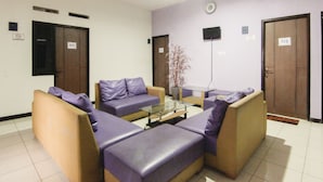 A waiting area with four sofas, a glass coffee table, and two doors marked 217 and 215. - Ungu Residence Syariah (Bandung)