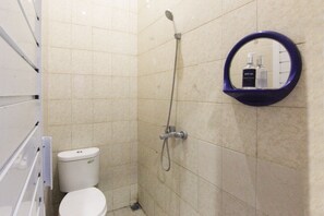A bathroom with a toilet, a shower, and a mirror with a soap dispenser. - Ungu Residence Syariah (Bandung)