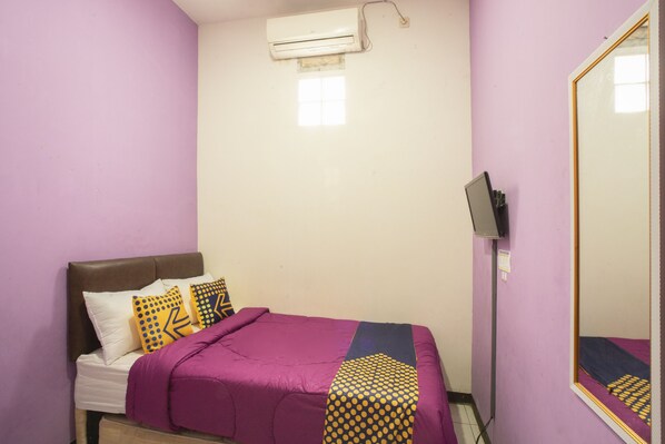 A bedroom with a bed, pillows, a blanket, an air conditioner, a mirror, and a television. - Ungu Residence Syariah (Bandung)