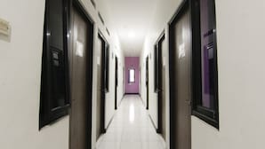 A long, narrow hallway with white tiled floors and dark doorways. - Ungu Residence Syariah (Bandung)
