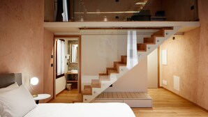 A modern bedroom with a large bed, a bedside table with a lamp, and a staircase leading to an upper level. - Ca' Dei Proverbi Suites - Wenice Deep Culture (Venice)