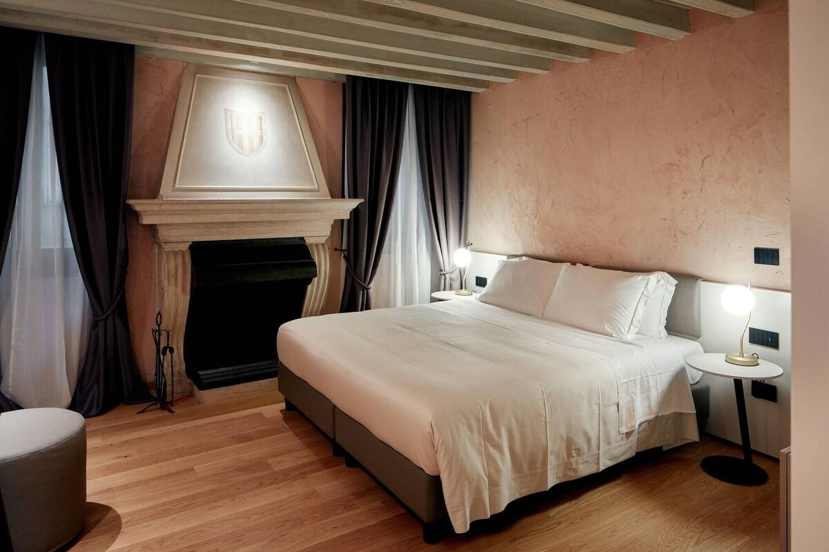 Ein Schlafzimmer mit einem Bett, einem Kamin, einem Nachttisch und einem Sessel.